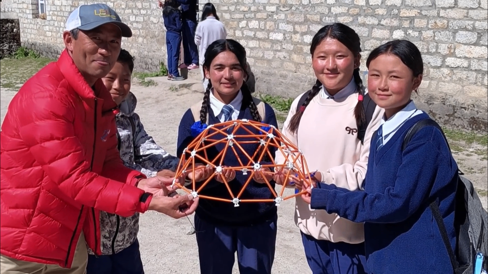Students and a mentor holding a geodesic dome model together in Nepal